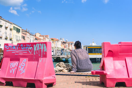 A person sitting by the canal between two 