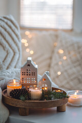 Winter home aromatherapy. Scented aroma candles, fir tree or spruce scent, decorative pine cones on wooden tray. Cozy atmosphere, relaxation, festive mood, interior decor bedroom, living room