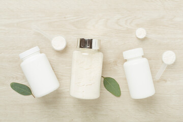 Jars with protein powder on wooden background, top view. Sports nutrition concept
