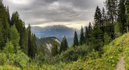 wild mountain forest with dramatic storm clouds and foresight onto steep cliffs and mountainside