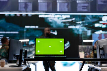 Laptop with green screen display running in military base of operations control tower, space used for gathering intelligence and support secret national defense missions. Command post.