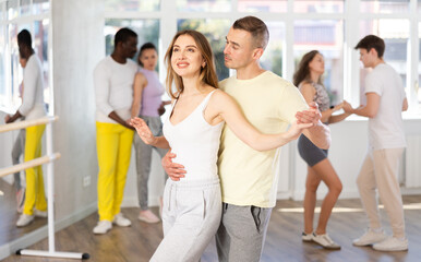 During rehearsal of reporting concert, guy and girlie participants of dance workshop perform figure...