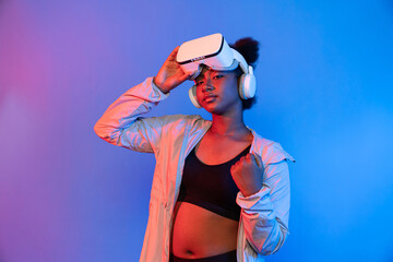 Profile young African sport woman wearing VR posing on blue neon lighting vibrant connecting digital futuristic technology virtual reality metaverse world exercise esports digital health. Contrivance.