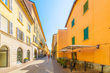 A woman walks her dog along and narrow cobblestone street of shops, sidewalk cafes and luxury boutiques in the historic old town of Lecco, Italy, on the shores of Lake Como.