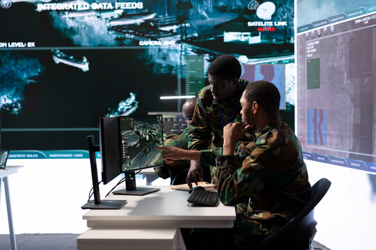 Team of military professionals in a control center monitors satellite intelligence, collecting real time information and transmitting details for a mission success. Help with decision making.