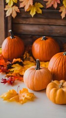 A fall background with orange pumpkins and fall leaves on a light surface. There are multiple pumpkins of various sizes.