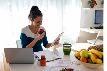 Focused multicultural expert with meal plan conducting web meeting using portable laptop at work.