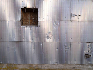A wooden access door on an old grain elevator with damaged corrugated metal siding