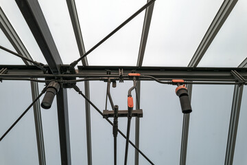 Metal beams and conduits on the ceiling of a patio enclosed by a transparent roof