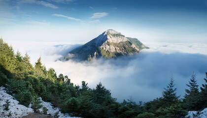 A serene mountain peak emerging from misty clouds, with distant tree lines fading into an un.