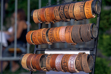 Leather wristbands displayed on stands, custom engraved, vintage style, outdoors at market, accessory fashion concept