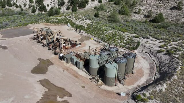 Aerial oil well rigs pumping storage Utah overhead. Oil wells, pumps ands storage tanks in a high mountain valley in north east Utah. Machinery and technology environmental pollution.