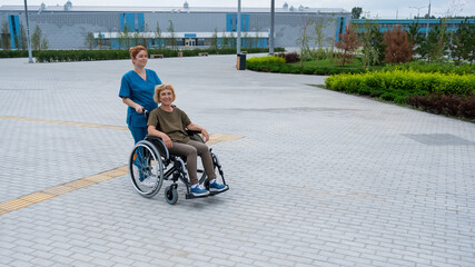 Caucasian nurse pushing elderly woman in wheelchair outdoors. 