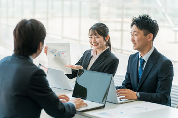 Fototapeta premium 企業のオフィスで笑顔で会議・ミーティング・商談をするビジネスマン・ビジネスウーマン 