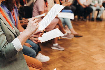 Choir rehearsal, vocal class singing in the auditorium hall, group of students on stage holding white sheets and singing, orchestra vocals class in music school with a teacher, adults sing in chorus © tsuguliev