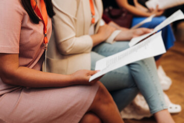 Choir rehearsal, vocal class singing in the auditorium hall, group of students on stage holding white sheets and singing, orchestra vocals class in music school with a teacher, adults sing in chorus