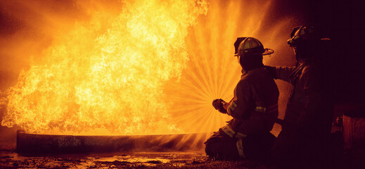 Two firefighters are sitting on the ground next to a fire