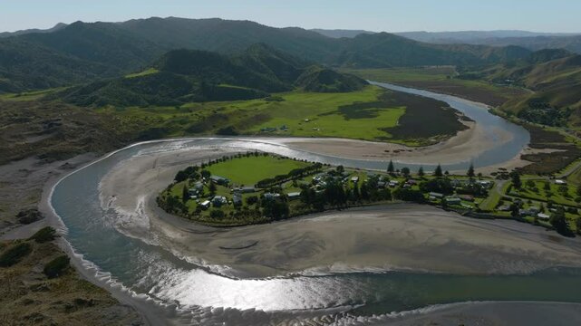 Aerial: Ocean beach, sand dunes, estuary, farmland in the rural town of Marokopa, Waikato, New Zealand.