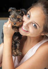 A young woman is holding a york shire puppy