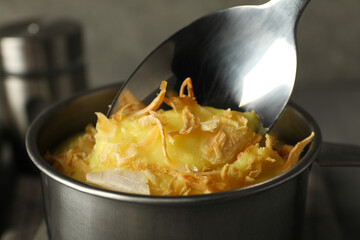 Cheese soup in a metal cup with kitchen utensils