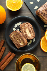 Roll cake in a bowl with fresh oranges on a dark background