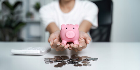 Hands Holding Pink Piggy Bank with Coins on Desk - Concept of Saving Money and Financial Planning
