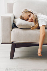 Obraz premium Young girl relaxing on a couch in a cozy room with scattered pillows, embracing a moment of tranquility
