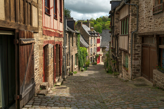Fototapeta View of the medieval street of the city with half-timbered houses descending to the embankment of the Rance River on a sunny summer day, Dinan, Cotes-d'Armor, Brittany, France