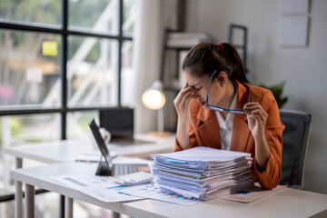 Tired asian businesswoman having headache while working with documents at office
