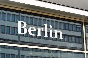 Schriftzug Berlin an einem Schaufenster der deutschen Hauptstadt mit der Spiegelung eines Hauses  