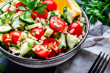 Vegetarian Tabbouleh Middle Eastern salad with bulgur, tomatoes, cucumbers and parsley.. Black background, top view