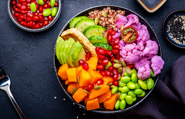 Vegan buddha bowl with vegetables, quinoa, edamame, tofu, quinoa and seeds, black background, top view