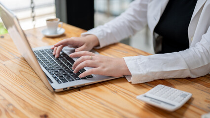 A businesswoman working on her laptop at her desk in the office, typing on the keyboard