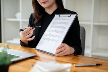 A professional female real estate agent showing and explaining a contract to a client.