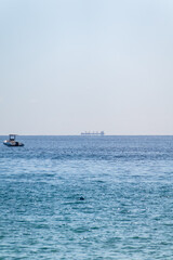 Calm blue sea with the silhouette of a large ship on the horizon