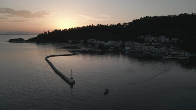 Drone view of small boat in Aegean Sea and Thassos Town (Limenas) harbour at sunrise, Thassos Town (Limenas), Thassos, Aegean Sea, Greek Islands, Greece, Europe