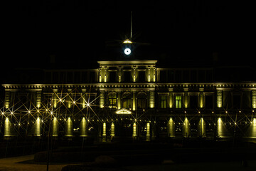 A grand view of Koceni Manor at night, beautifully lit with golden lights that create a starburst...