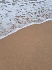 
It is a sandy beach with waves crashing in.