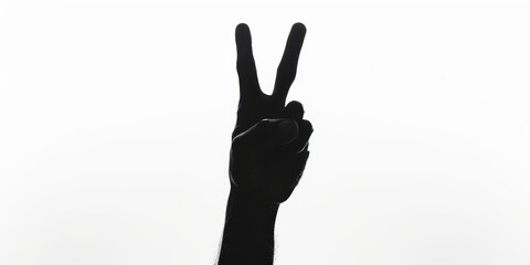 Fototapeta premium A dark silhouette of a hand creating a peace sign against a minimalist white background in a simple yet striking composition