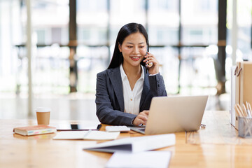 Fototapeta premium Business Asian woman freelancer is working her job on a laptop computer and phone call in the office. Doing accounting analysis report real estate investment data, Financial and tax systems concept. 