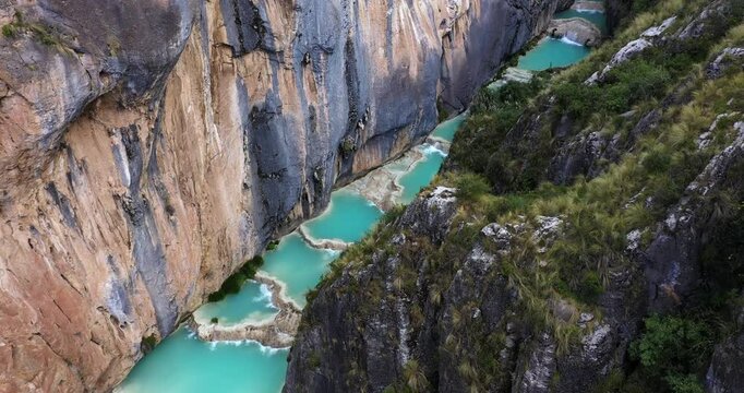 Amazing drone shot of the beautiful Millpu lake with turquoise water and vegetated mountains on a sunny day with beautiful colors.