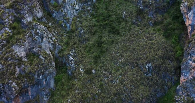 Beautiful drone shot of a mountain with rock and vegetation around Millpu Lake in Ayacucho, Peru on a cloudy day.