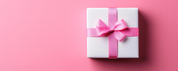 A beautifully wrapped gift box with a pink bow, set against a vibrant pink background, perfect for celebrations and occasions.