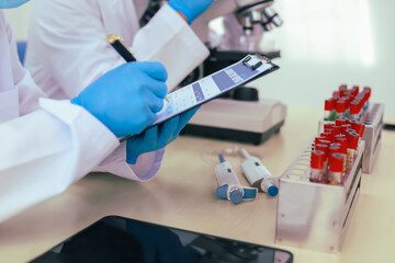 Two male researchers are conducting chemical research in a science lab, carefully analyzing substances at a desk filled with scientific instruments and chemical solutions in a well-organized