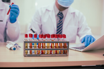 Two male researchers are conducting chemical research in a science lab, carefully analyzing...