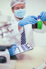 Two male researchers are conducting chemical research in a science lab, carefully analyzing substances at a desk filled with scientific instruments and chemical solutions in a well-organized