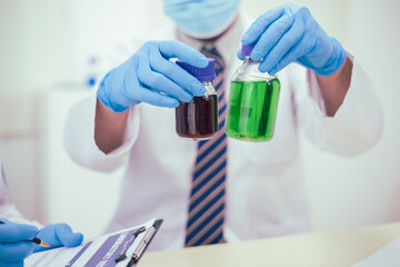 Two male researchers are conducting chemical research in a science lab, carefully analyzing substances at a desk filled with scientific instruments and chemical solutions in a well-organized