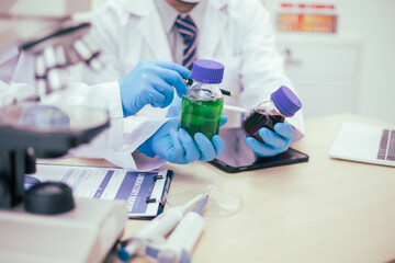 Two male researchers are conducting chemical research in a science lab, carefully analyzing substances at a desk filled with scientific instruments and chemical solutions in a well-organized
