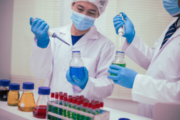 Fototapeta premium Two male researchers are conducting chemical research in a science lab, carefully analyzing substances at a desk filled with scientific instruments and chemical solutions in a well-organized