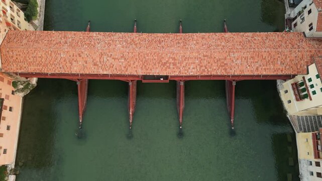 Covered Bridge Ponte Vecchio Crossing River Brenta In Bassano del Grappa, Italy. drone tilt-up, pullback